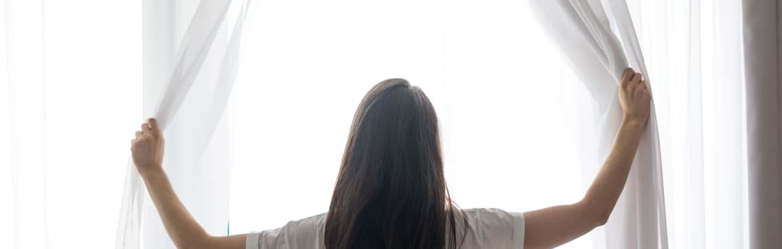 Mujer-abriendo-cortinas-luz-natural